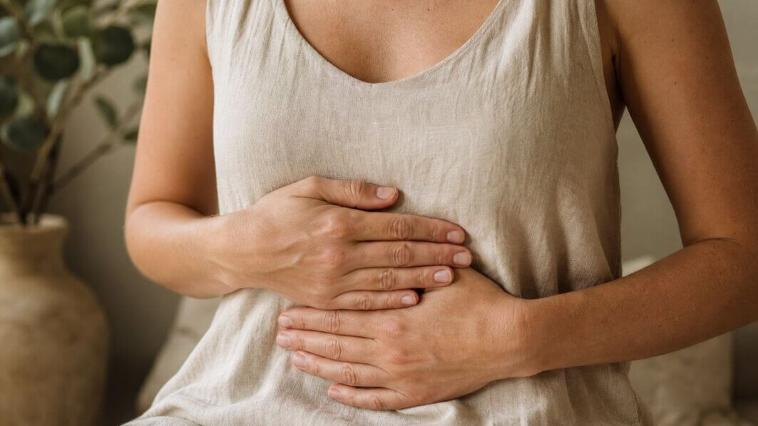 Hände liegen sanft auf dem Bauch – Symbol für Vagusnerv-Aktivierung, Körperbewusstsein und die Darm-Hirn-Achse.