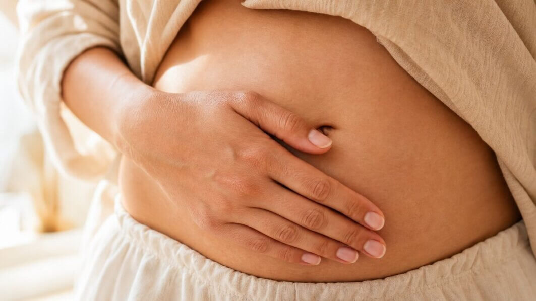 Frau berührt achtsam ihren Bauch – Körperbewusstsein bei Cortisol-bedingtem Bauchfett.