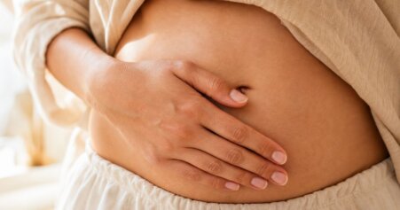 Frau berührt achtsam ihren Bauch – Körperbewusstsein bei Cortisol-bedingtem Bauchfett.