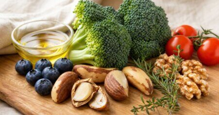 Paranüsse, Brokkoli, Blaubeeren und Walnüsse auf einem Holzbrett als selenreiche, anti-entzündliche Ernährung bei Morbus Basedow.