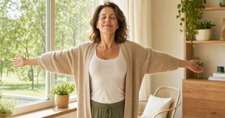 Frau Mitte 30 sitzt entspannt am Küchentisch mit einer gesunden Mahlzeit – Symbol für Stressabbau und bewusste Ernährung gegen Stressbauch.